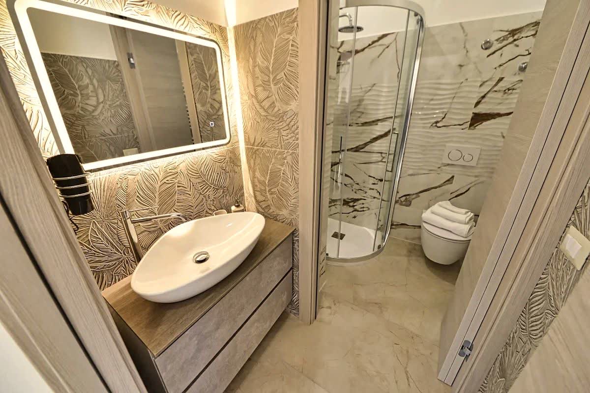 Bagno con carta da parati a palme in rilievo e specchio retroilluminato