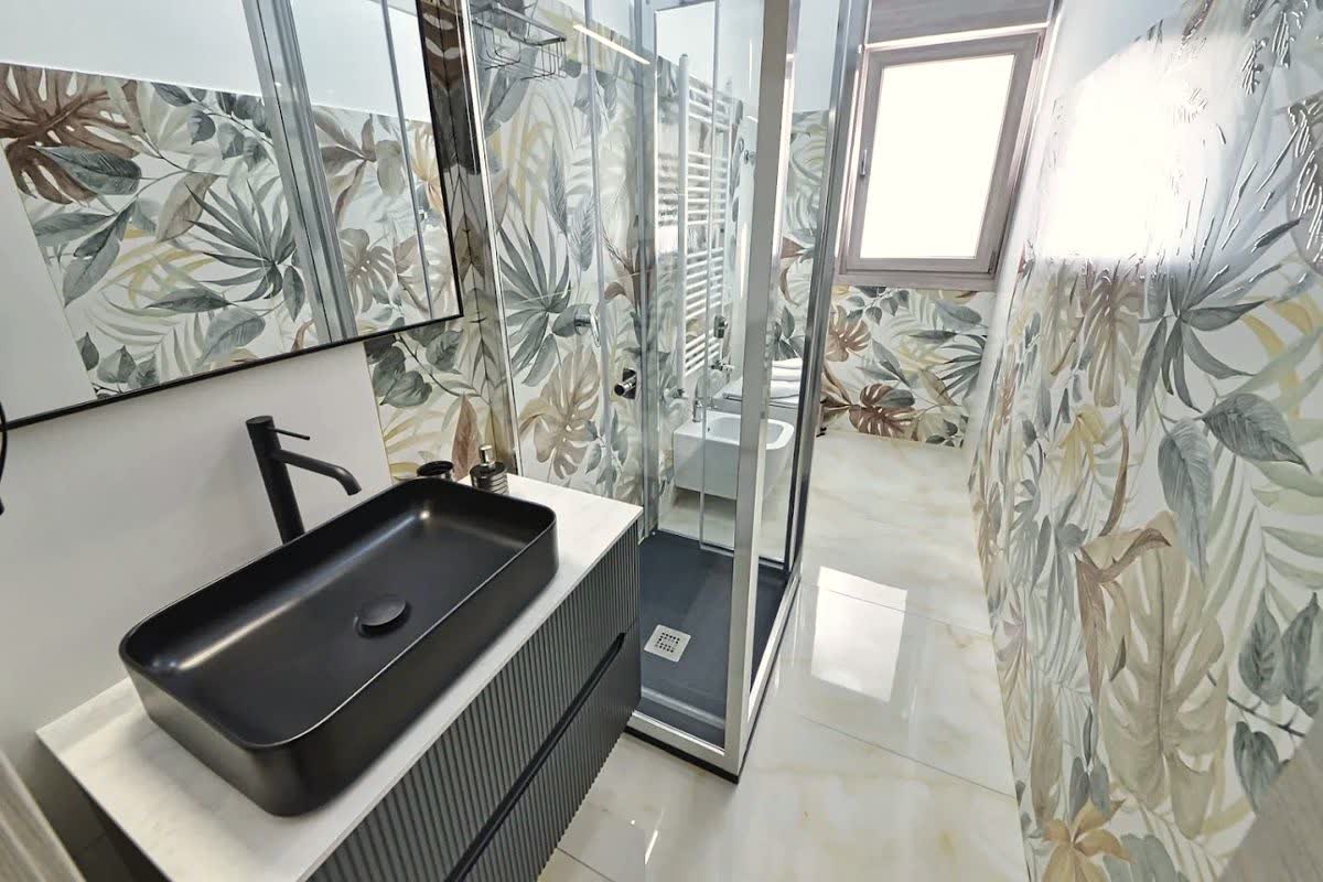 Bagno tropicale con lavabo nero opaco e marmo lucido
